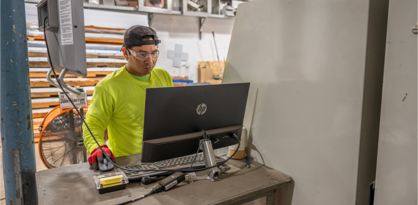 Campany shop worker in safety glasses at fabrication equipment inside the West Palm Beach metal shop