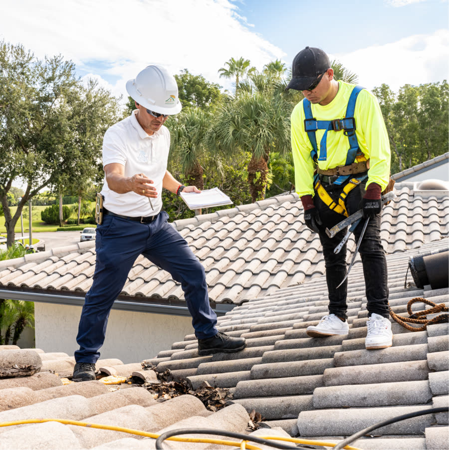 Campany supervisor with checklist pointing out debris in a tile roof valley during a Gold Umbrella inspection